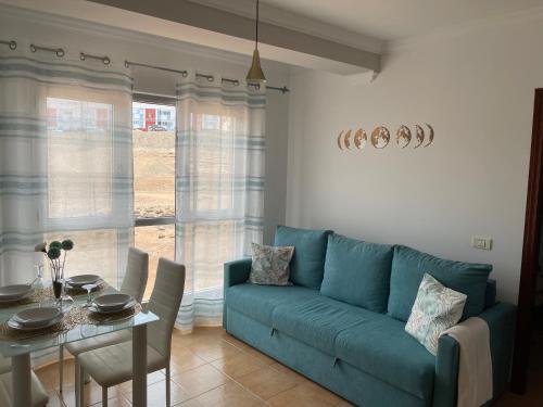 un soggiorno con un divano blu e un tavolo di ÁTICO "TURQUESA BEACH" CON PISCINA, TERRAZA y BARBACOA a Sardina