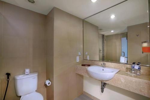 a bathroom with a sink and a toilet and a mirror at favehotel Sunset Seminyak in Seminyak