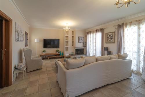 sala de estar con sofá blanco y TV en Celine Deluxe Apartment en Lefkada