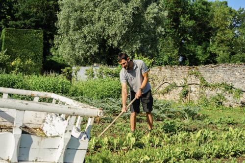 a man standing in a garden with a rake at Hostellerie De Levernois in Levernois