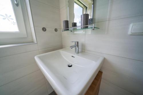 a white bathroom with a sink and a mirror at Appartments Kramer in Schiefling am See