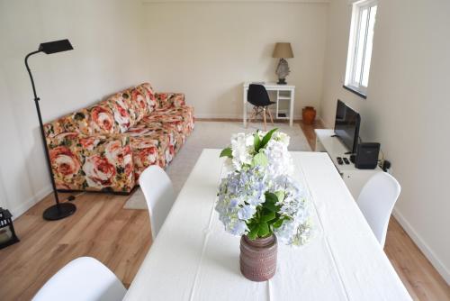 a living room with a white table with flowers on it at Nia Azorean Apartments in Horta