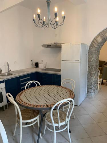 une cuisine avec une table et un réfrigérateur blanc dans l'établissement La Maison de Leontine, à La Livinière