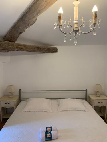 1 dormitorio con cama blanca y lámpara de araña en La Maison de Leontine, en La Livinière