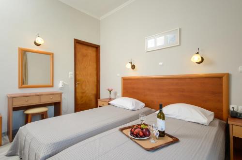 a bed with a tray of fruit and a bottle of wine at Naxos Hotel Savvas in Naxos Chora