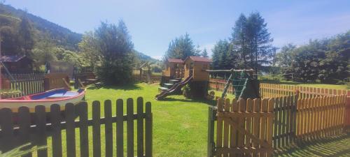 a wooden fence with a playground in a yard at Stanica pod Zadzierną Domki całoroczne in Lubawka