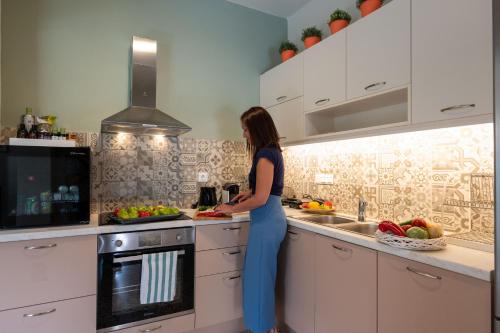 a woman standing in a kitchen preparing food at Tinas Home - Kalamata Mediterranean Villas in Kalamata