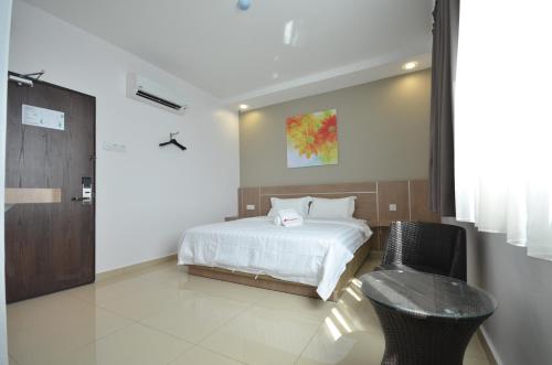 a bedroom with a bed and a chair in it at AST Hotel in Alor Setar