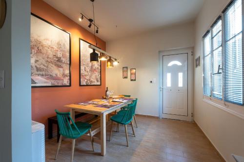 a dining room with a table and green chairs at Tinas Home - Kalamata Mediterranean Villas in Kalamata