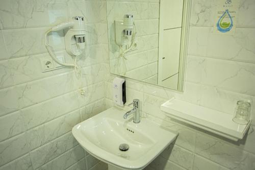 a white bathroom with a sink and a mirror at B Hotel Bishkek in Bishkek