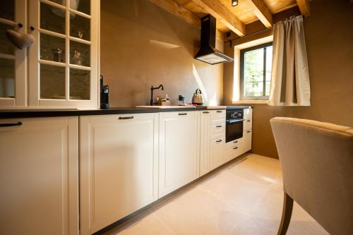 a kitchen with white cabinets and a sink at Paddock Lodge - Suites Wellness & Chambres d'hôtes in Stoumont