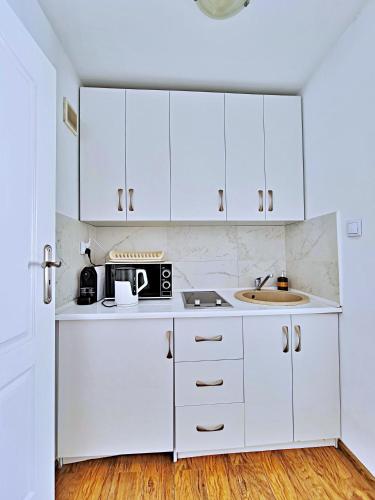 a white kitchen with white cabinets and a sink at Perfect Stay - "Campari Glam Apartments" in Toruń