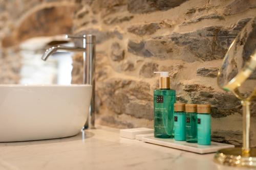 a bathroom counter with two bottles of soap and a sink at Paddock Lodge - Suites Wellness & Chambres d'hôtes in Stoumont