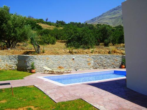 a swimming pool in a yard with a stone wall at Villa Alexander 2 in Triopetra