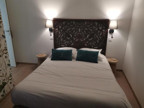 a bedroom with a large bed with two green pillows at Logis Le Relais du Chapeau Rouge in Saint Loup Lamaire