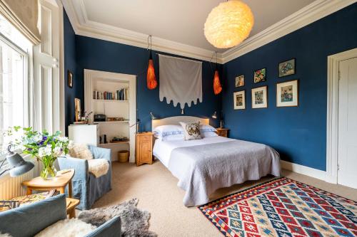 ネアンにあるWashington Houseの青い壁のベッドルーム1室、ベッド1台、ソファが備わります。