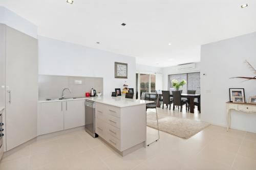 una cucina con armadi bianchi e una sala da pranzo di Central Warrnambool Townhouse a Warrnambool