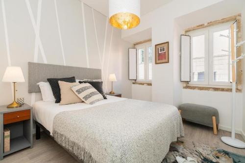 a white bedroom with a bed and a window at Designer Flats in Lapa by LovelyStay in Lisbon