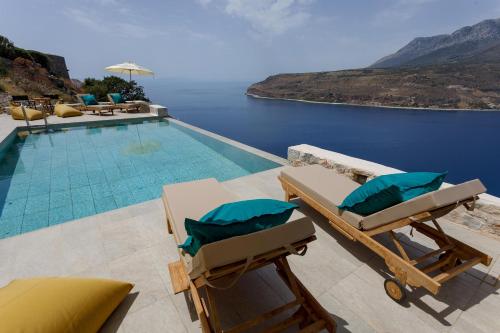 a pool with two lounge chairs and a view of the water at ERMIS-APEA Villas in Limeni