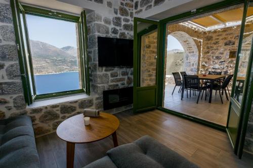 a living room with a table and chairs and a large window at ERMIS-APEA Villas in Limeni