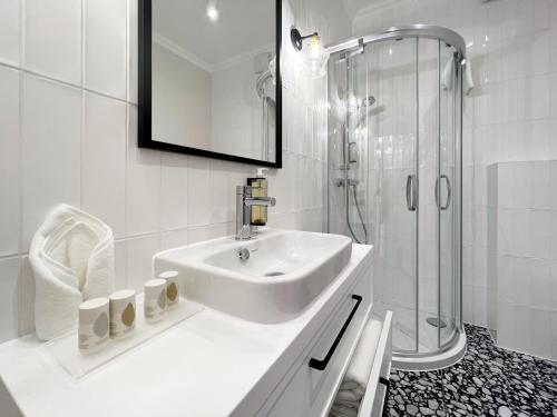 biała łazienka z umywalką i prysznicem w obiekcie Kurkowa Apartments w Szczecinie