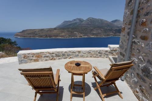 a table and chairs on a patio with a view of the ocean at ARIS-APEA Villas in Limeni