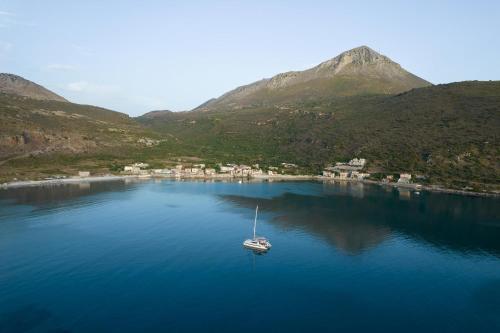a boat in a large body of water with mountains at ARIS-APEA Villas in Limeni