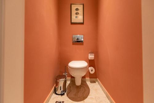 a small bathroom with a toilet in an orange wall at Tinas Home - Kalamata Mediterranean Villas in Kalamata