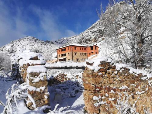 a building in the snow in front of a mountain at Las Aliagas Apartamentos Rurales in Megina