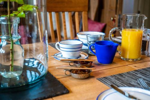 a wooden table with plates and cups and orange juice at Washington House in Nairn