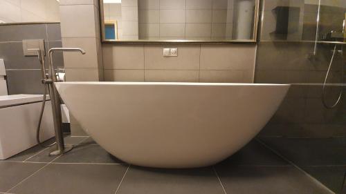 a white tub in a bathroom with a mirror at Old Town Apartment in Pärnu