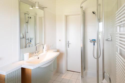 biała łazienka z umywalką i prysznicem w obiekcie Heide Idyll w mieście Wenningstedt