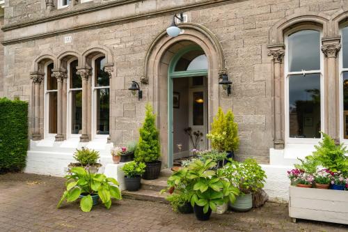 a building with potted plants in front of a door at Washington House in Nairn
