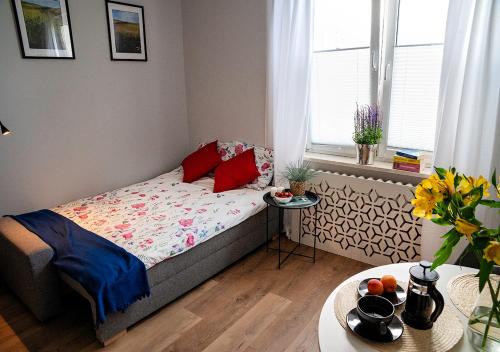 Habitación pequeña con cama con almohadas rojas en Valdi Apartament, en Gdynia