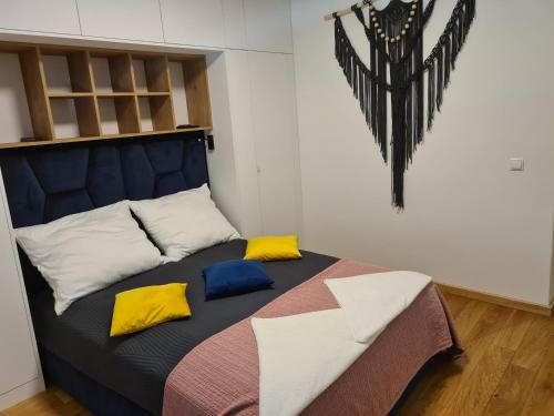 a bed with colorful pillows on it in a room at Apartamenty Osmolice w Stawach in Dęblin