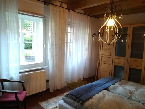 una camera con letto, lampadario a braccio e finestra di Ferienwohnung im historischen Zentrum 25562 a Weener