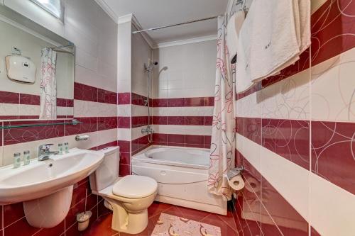 La salle de bains est pourvue d'un lavabo, de toilettes et d'une baignoire. dans l'établissement Colorful 2BD Apartment with Indoor Fireplace and Mountain View, à Pamporovo
