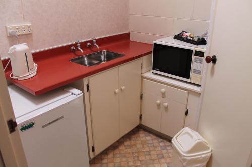 a small kitchen with a sink and a microwave at Riverview Motel in Whanganui