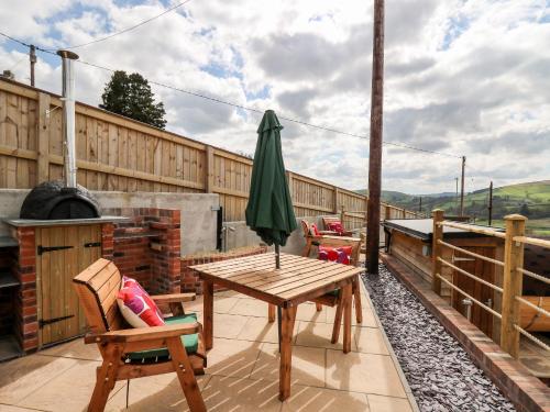 a patio with a table and chairs and an umbrella at The Old Cobblers Shop in Llandrindod Wells