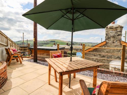 a wooden table with an umbrella on a patio at The Old Cobblers Shop in Llandrindod Wells