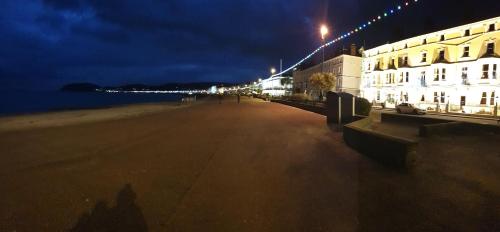 a beach at night with a building and the ocean at The Senarth in Llandudno