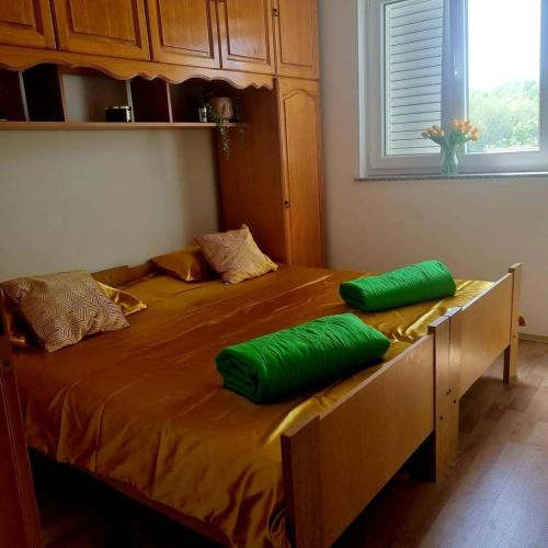 a bed with two green pillows on top of it at Apartments MaRo in Pag