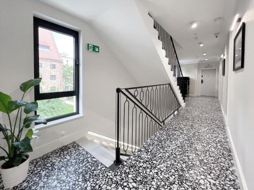 a hallway with black and white flooring and a window at Kurkowa Apartments in Szczecin