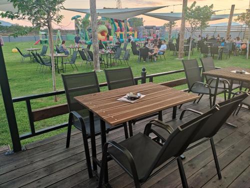 a wooden table and chairs on a deck with a playground at Hotel Alexandros in Doxato