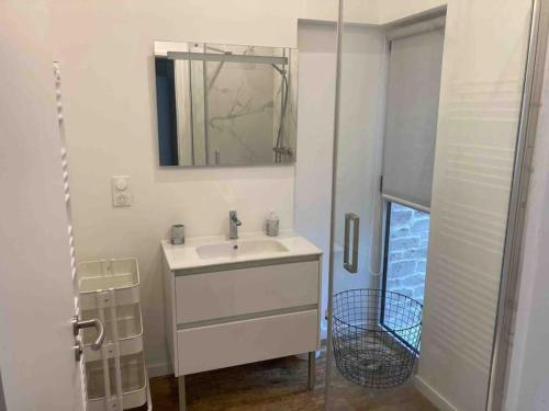 La salle de bains blanche est pourvue d'un lavabo et d'un miroir. dans l'établissement Jolie maison de pêcheur ARAGO aux Sables d'Olonne, à Les Sables-dʼOlonne