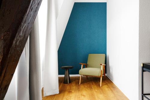 a chair in a room with a blue wall at Hotel Waren-Alte Warener Zeitung in Waren