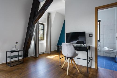 um quarto com uma secretária, uma televisão e uma cadeira em Hotel Waren-Alte Warener Zeitung em Waren