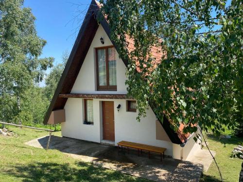 a house with a thatched roof with a bench in front at Vikendica Stojanović in Mionica