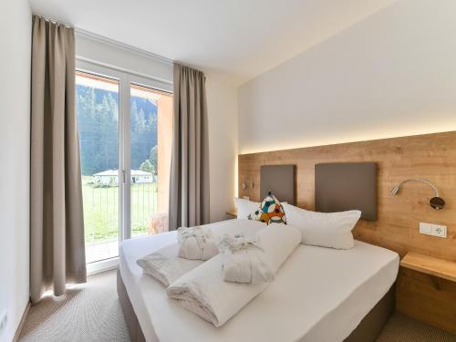 a bedroom with a large white bed with a window at Chalet in der Alpine Lodge Klösterle am Arlberg in Klösterle