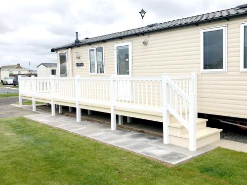 a mobile home with a porch and a white railing at Golden Palm Getaway's PG143 in Skegness